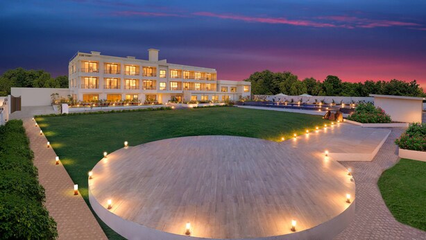 A modern hotel with a spacious courtyard, well-lit pathways, and a large building with multiple balconies. - Lemon Tree Resort, Somnath (Veraval)