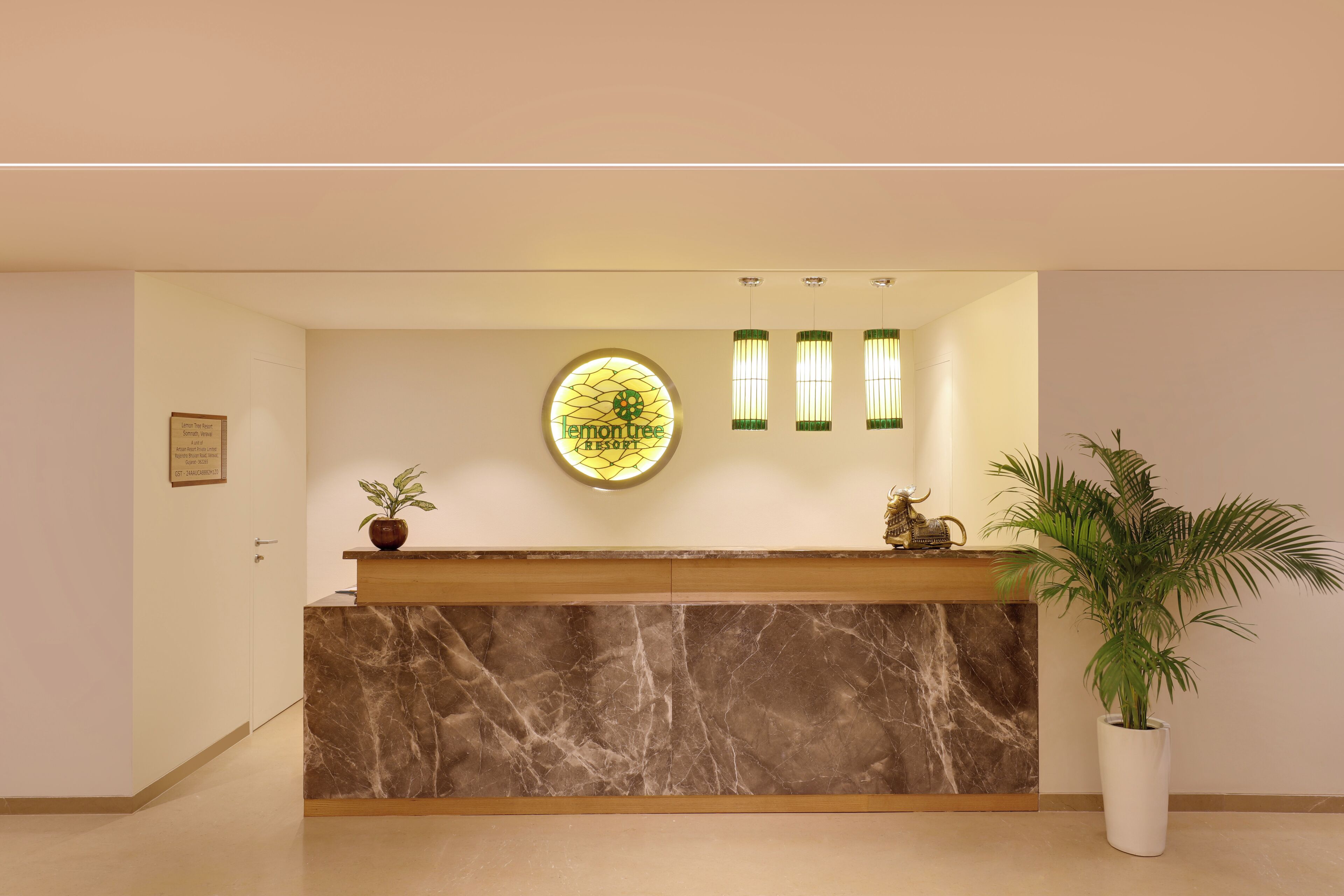 Una recepción con encimera de mármol, una planta en maceta y una ventana circular de vitral con el texto "Lemon Tree Resort".