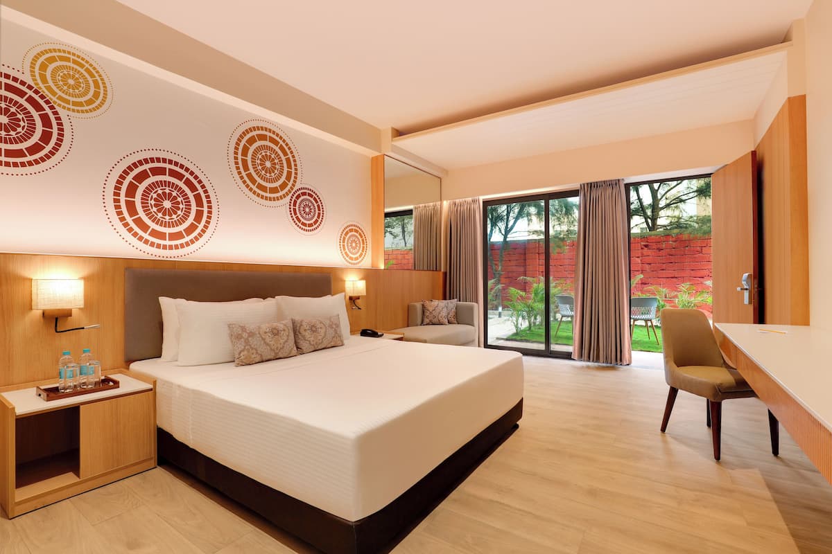 A modern hotel room with a large bed, a desk, and a view of the outdoors.