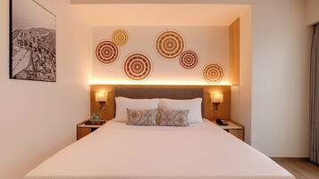 A hotel room with a large bed, two bedside tables, a headboard with circular wall art, and a framed picture on the wall.