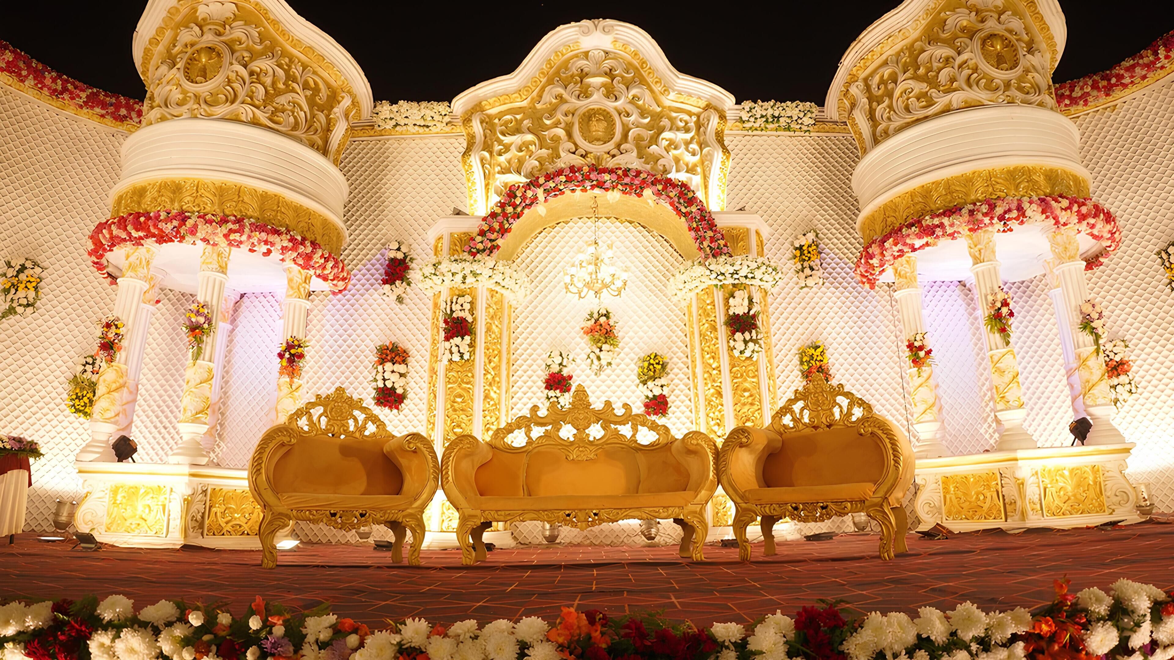 A stage with ornate golden chairs, a floral arch, and a textured wall backdrop.