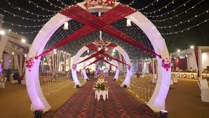 An indoor venue with a central aisle, white drapery, and string lights. - Nirmal Resort (Bareilly)