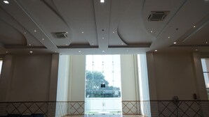 A spacious room with a high ceiling, large windows, and a view of trees outside. - Nirmal Resort (Bareilly)