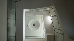 A modern interior with a glass staircase leading to a circular ceiling feature. - Nirmal Resort (Bareilly)
