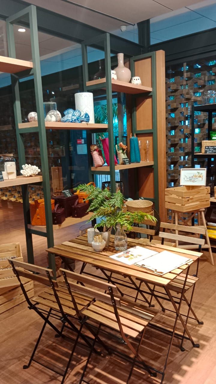 Ein Zimmer mit einem Holztisch und Stühlen, Regalen mit Dekoration und Blick durch eine Glaswand.