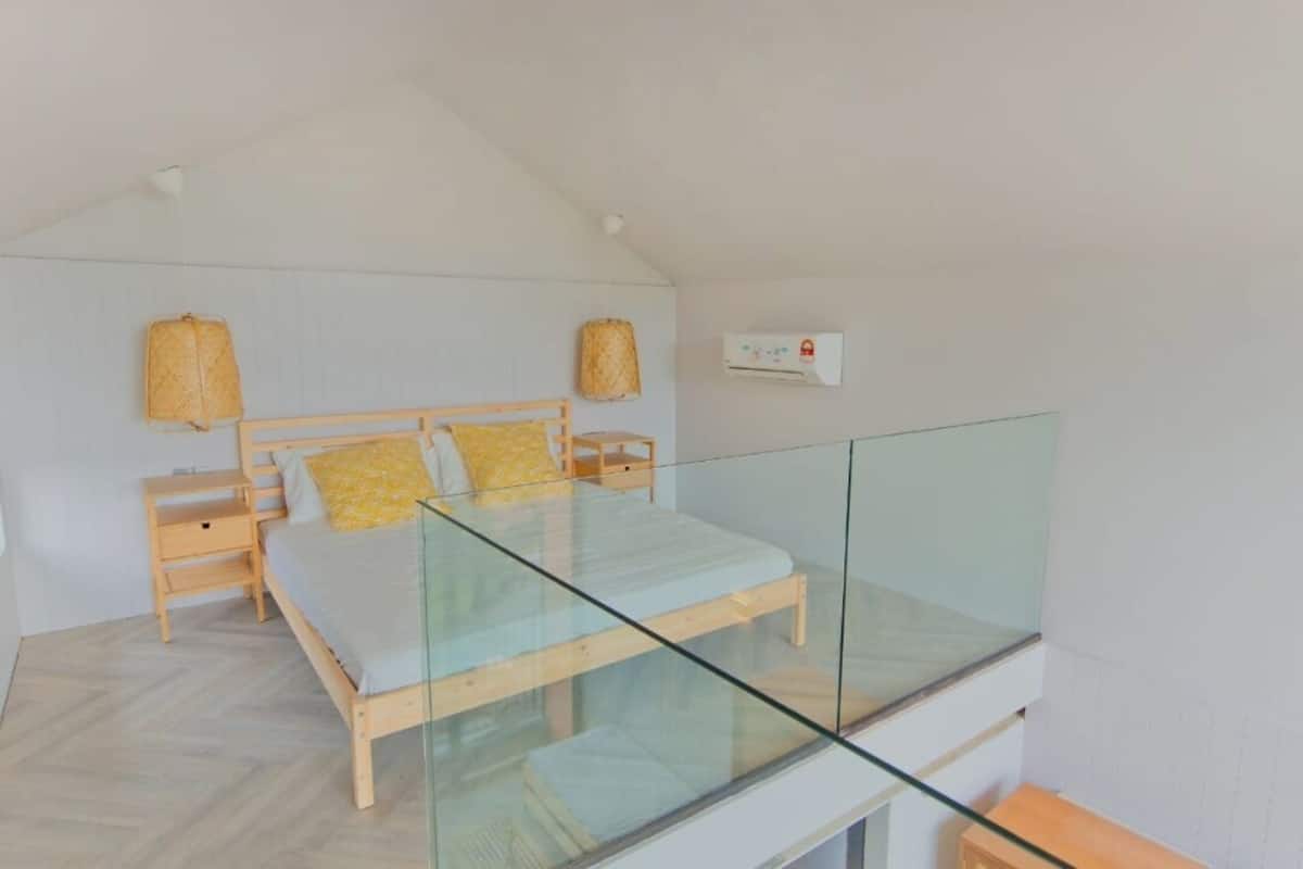 A modern bedroom with a glass balcony, a wooden bed, and a small bedside table.