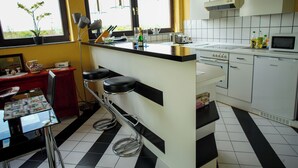 Eine Küche mit Bar, einem Esstisch und Stühlen. Es gibt Barhocker, eine Mikrowelle und ein Spülbecken.