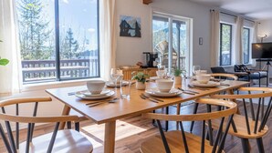A dining area with a wooden table set for four, surrounded by wooden chairs.