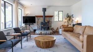 A living room with a stone fireplace, leather sofa, and a round wooden coffee table.