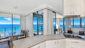 Una cocina moderna con una isla grande, armarios blancos y vistas al océano.