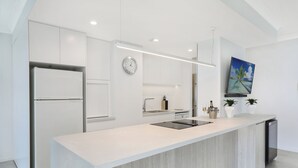 Una cocina moderna con una isla grande, armarios blancos y horno empotrado.