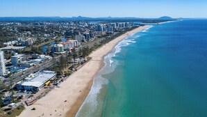 Vista aérea de una ciudad costera con una playa extensa, edificios altos y aguas azules cristalinas.
