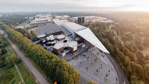 An aerial view of a modern building complex with multiple structures, surrounded by greenery and a parking area. - Apartment in Essen with Balcony & Garden (Essen)