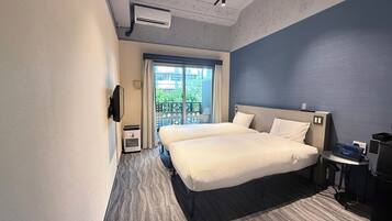 Una habitación de hotel moderna con una cama grande, un escritorio con una computadora portátil, un televisor y un balcón con vistas.
