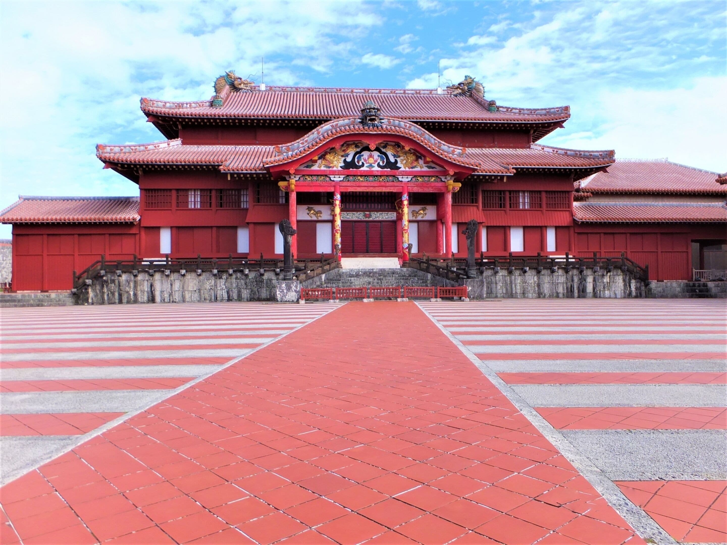 Un bâtiment traditionnel de couleur rouge, avec un chemin piétonnier dallé menant à l’entrée.