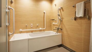 Un baño moderno con bañera, barras de apoyo y un perchero para toallas.