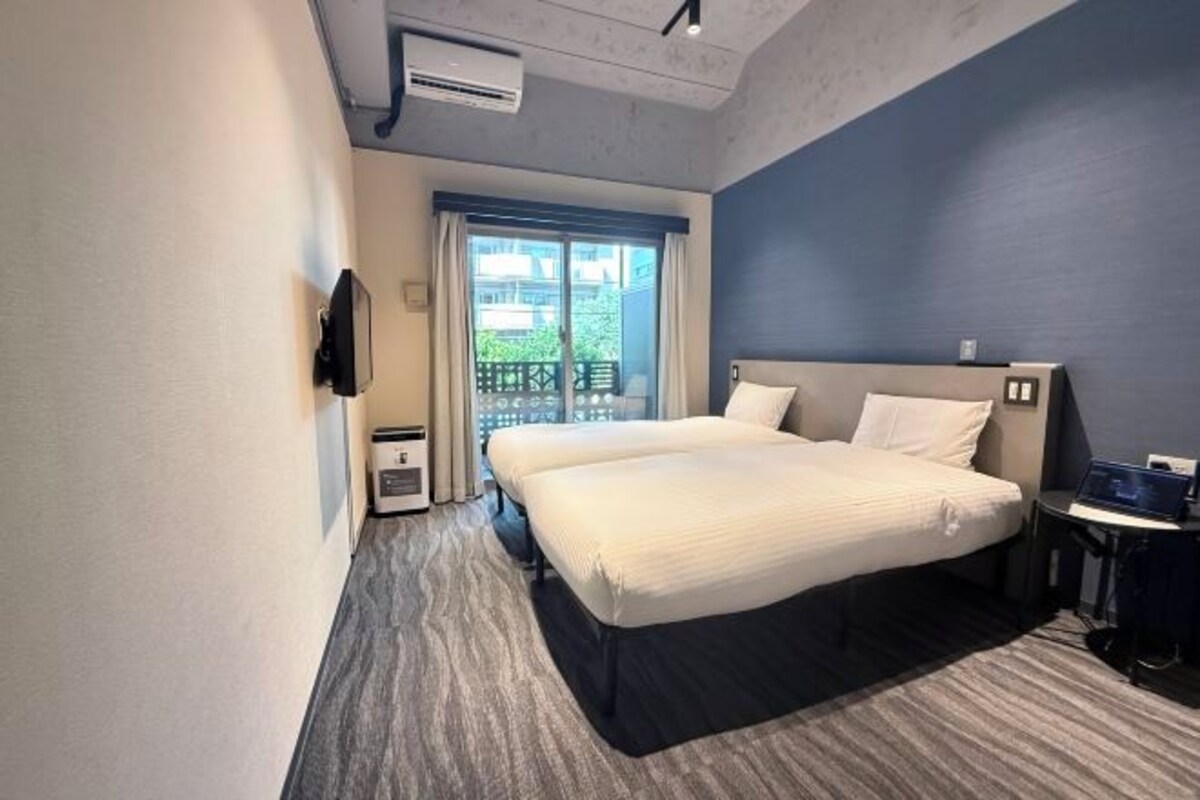 Habitación de hotel con cama, escritorio, silla, televisión y ventana con vistas.