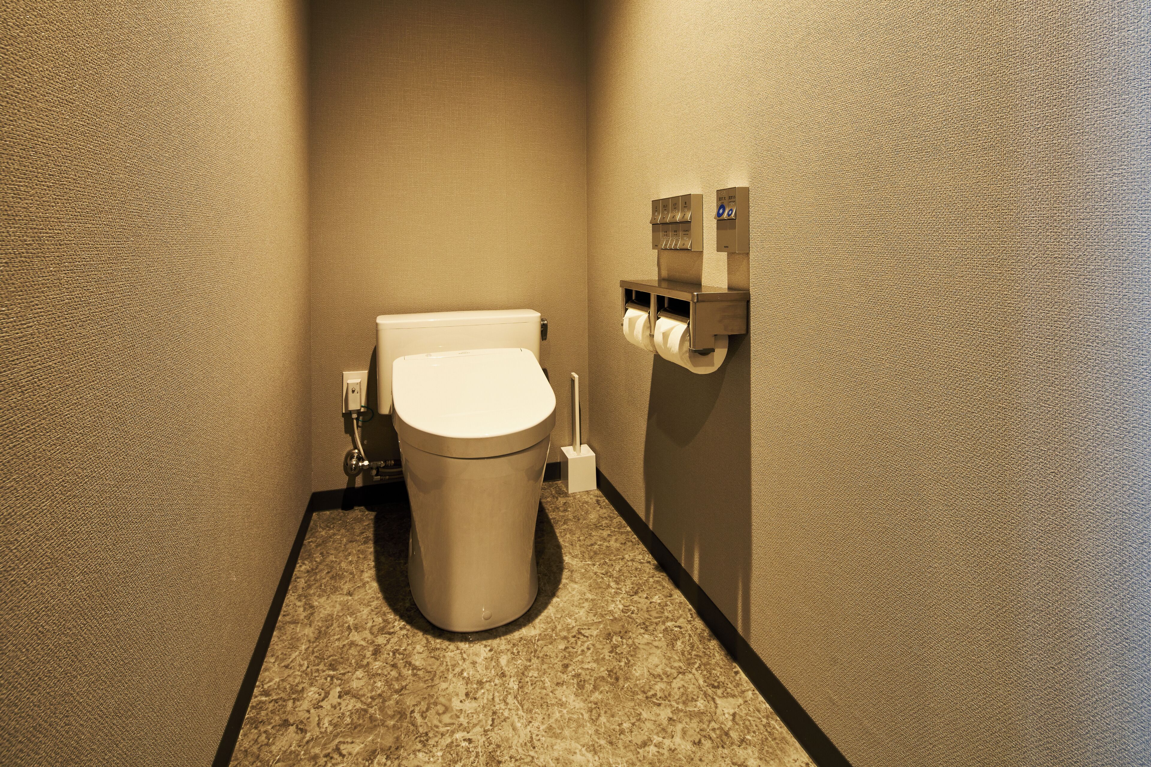 A compact bathroom with a toilet, a paper towel dispenser, and a hand dryer.