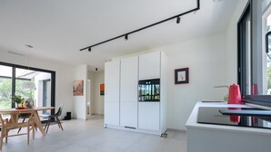 A modern kitchen with white cabinetry, a dining area with a wooden table and chairs, and a large window providing natural light. - Villa Port des Vins – Luxury villa in Salernes with heated pool (Salernes)