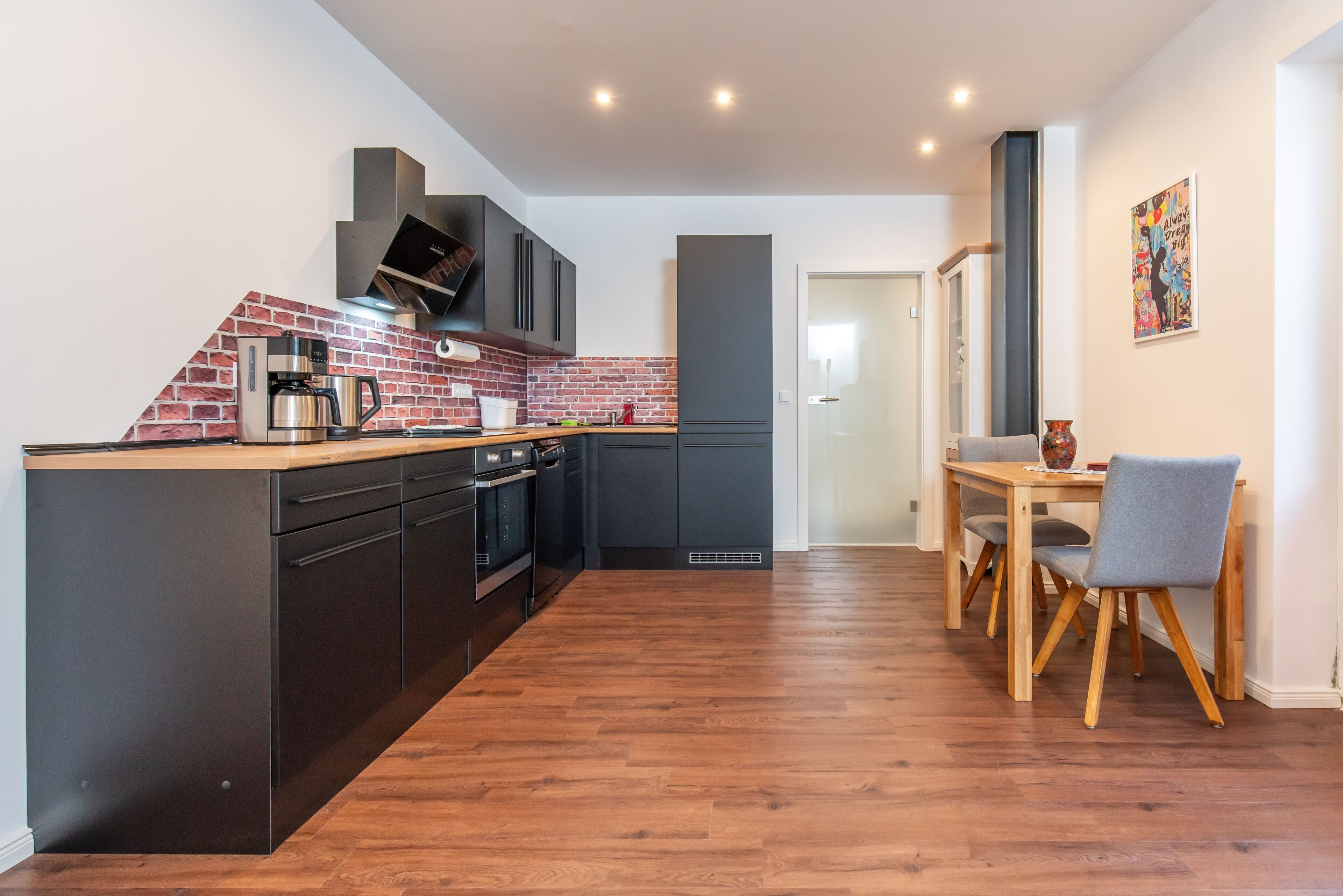 Offene vollausgestattete Küche mit Kühlschrank, Spülmaschine, Ceranfeld und Backofen, Kaffeemaschine und Wasserkocher, Esstisch mit Stühlen