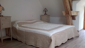 Ein Schlafzimmer mit Bett, Nachttisch, Kommode und Holzbalken.