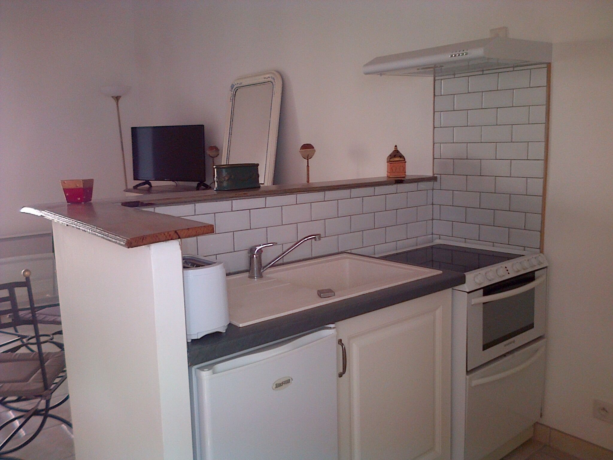 A compact kitchen with a sink, stove, and a small refrigerator.