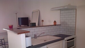 Eine kleine Küche mit Spüle, Herd und Kühlschrank.