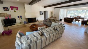 Ein Wohnzimmer mit Sofa, Couchtisch, Fernseher, Kamin und Kunstwerken an den Wänden.