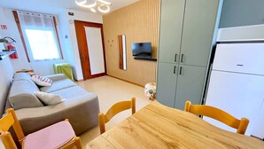 Un espace de vie compact comprenant un canapé, une table à manger et un téléviseur fixé au mur.