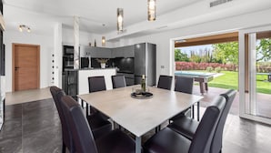 A modern kitchen with dark cabinets, a central island, and pendant lighting. - Villa in Istria with Heated Eco Pool (Brtonigla)
