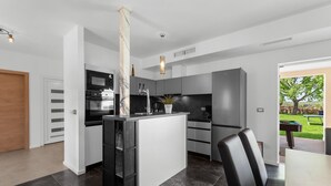 A modern kitchen with a central island, built-in appliances, and a view of the outdoor area. - Villa in Istria with Heated Eco Pool (Brtonigla)