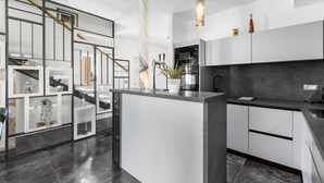 A modern kitchen with a central island, white cabinetry, and a marble backsplash. - Villa in Istria with Heated Eco Pool (Brtonigla)