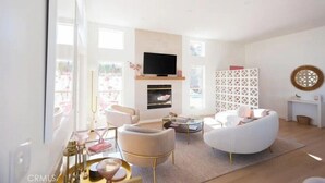 Un salon moderne doté d’une cheminée, de sièges confortables et d’un téléviseur.