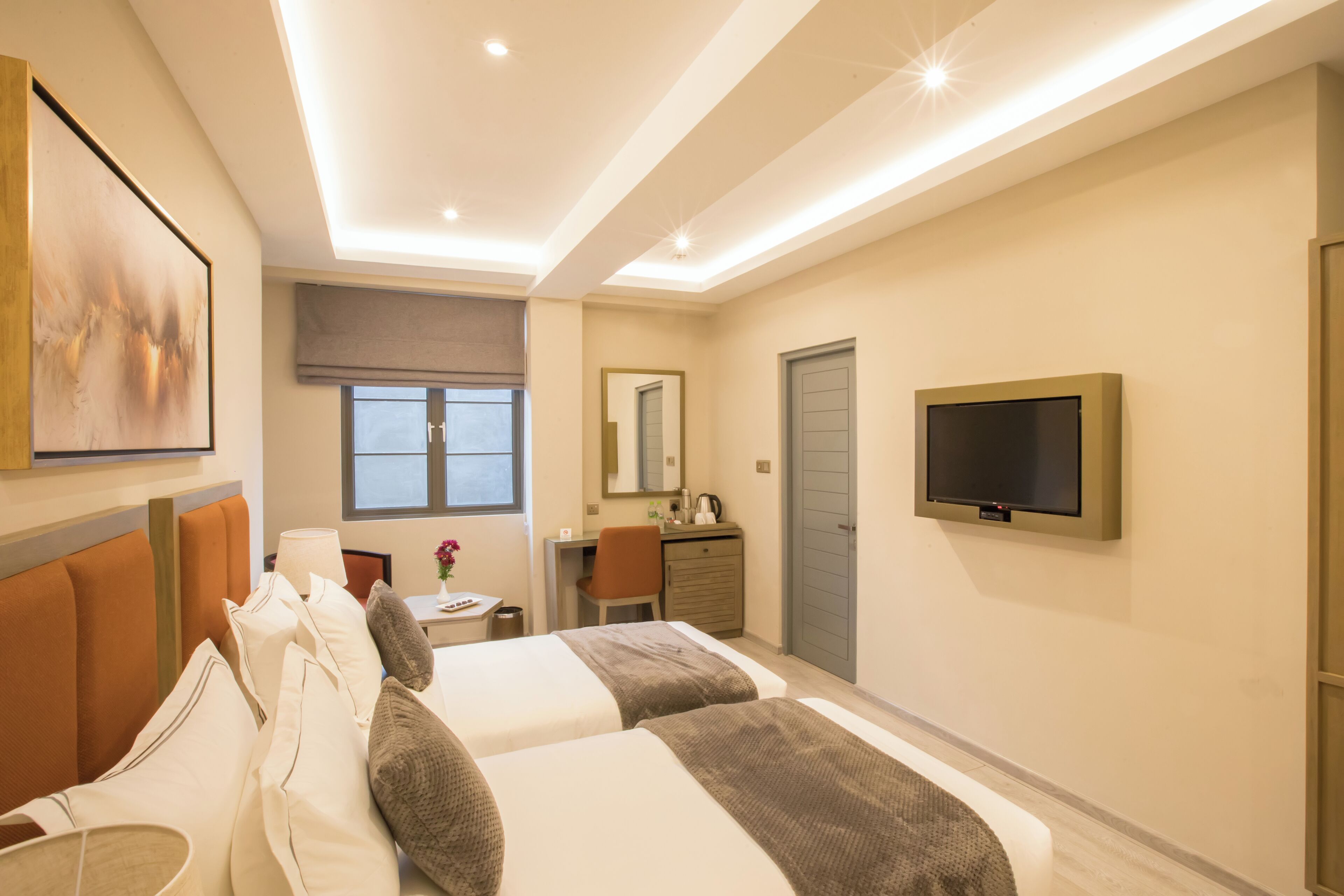 Een hotelkamer met twee bedden, een bureau, een stoel, een televisie en een raam.