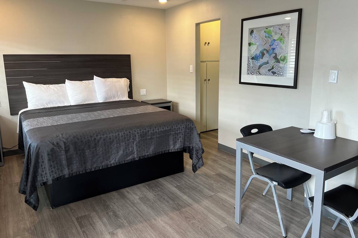A hotel room with a bed, bedside table, desk, and chair.