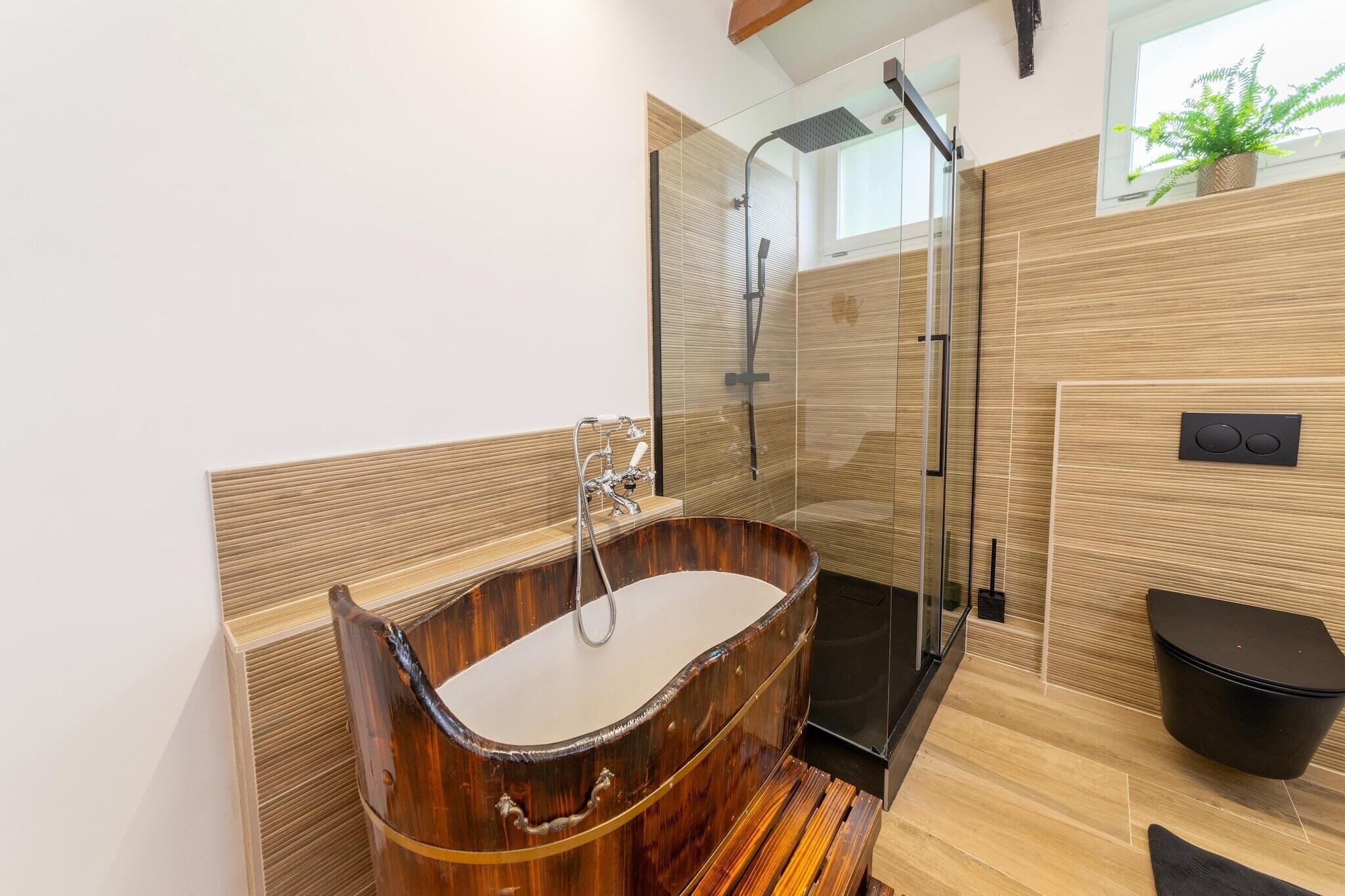 Un bagno moderno con una vasca da bagno in legno, un box doccia in vetro e un water nero.