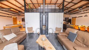 Un vaste espace de vie agrémenté de canapés en cuir, d’une table en bois au centre et d’une cheminée moderne.