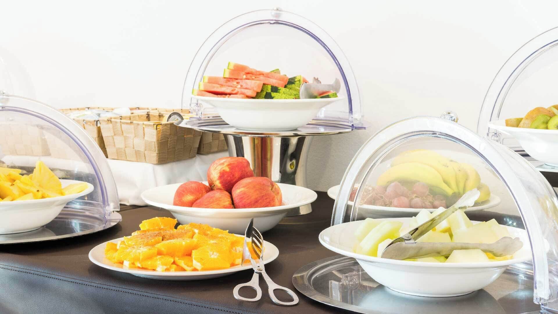 A buffet with various fruits and a pair of scissors on a table.