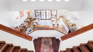 Un comedor amplio con varias mesas y sillas, una escalera que conduce a un nivel superior y una mesa de buffet con diversos alimentos.