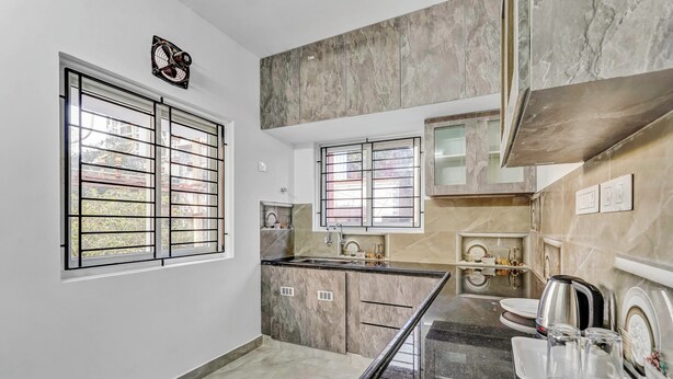 Una cocina moderna con encimeras de mármol, un lavamanos empotrado y una ventana con barrotes de metal.