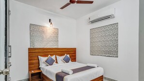 Un dormitorio moderno con una cama de madera, una mesita de noche, un ventilador de techo y un equipo de aire acondicionado.