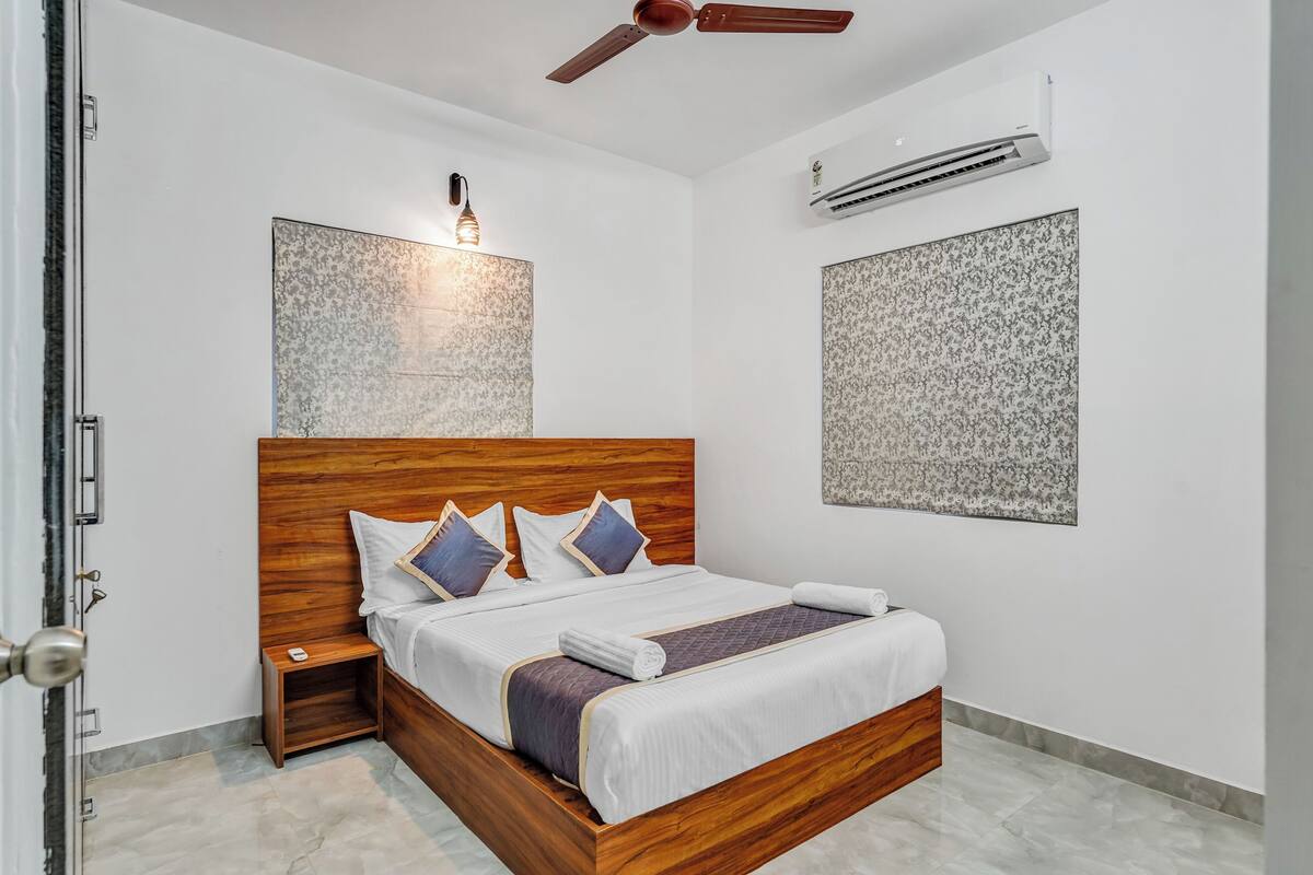 Ein modernes Schlafzimmer mit einem hölzernen Bett, einem Nachttisch, einem Deckenventilator und einer Klimaanlage.