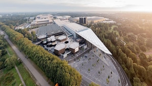 An aerial view of a modern building complex with multiple structures, surrounded by trees and open spaces. - Apartment in Essen with Garden Terrace (Essen)
