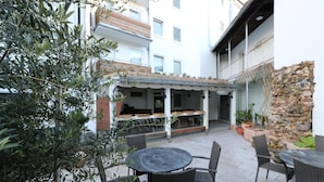 An outdoor patio area with a round table and chairs, a covered seating area, and potted plants. - Apartment in Essen with Garden Terrace (Essen)