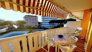 Ein Balkon mit Tisch und Stühlen, ein Schwimmbad und Gebäude im Hintergrund.