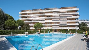 Ein mehrstöckiges Hotel mit Schwimmbad, Außenbereich und blauem Himmel.