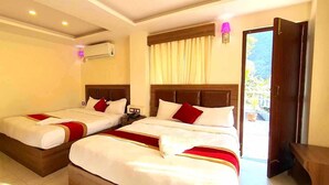 A hotel room with two beds, a ceiling fan, an air conditioning unit, and a view of the outdoors. - River Beach Resort - Trishuli (Dhussa)