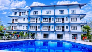A multi-story hotel with a swimming pool, balconies, and a clear blue sky. - River Beach Resort - Trishuli (Dhussa)