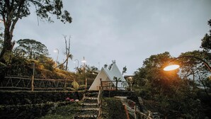 A white tent-like structure on a hillside with a stone staircase leading up. - Alam Caldera Camp & Resto  (Kintamani)