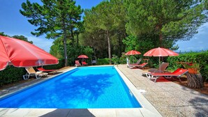 A swimming pool with red umbrellas and lounge chairs. - Lovely apartment for 6 guests with pool, WIFI, veranda and panoramic view, close to San Gimignano (Montaione)